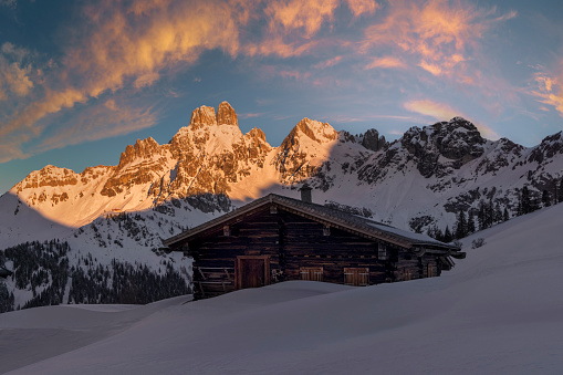 Wooden hut in winter by Mount Dachstein with Mount Bischofsmütze, Sulzenalm at sunrise with alpenglow