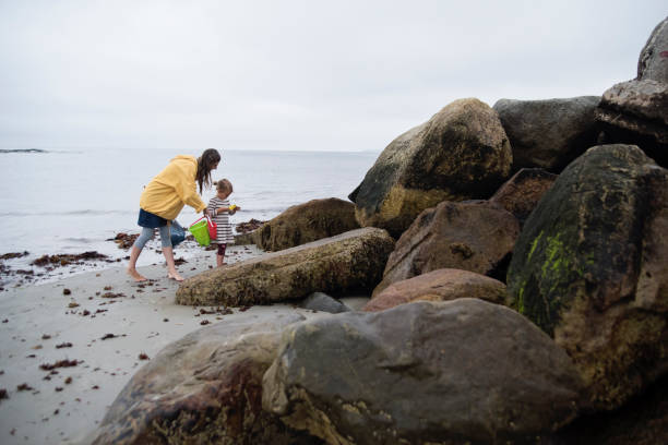 istock Mother and daughter on beach on overcast day. 1368968771