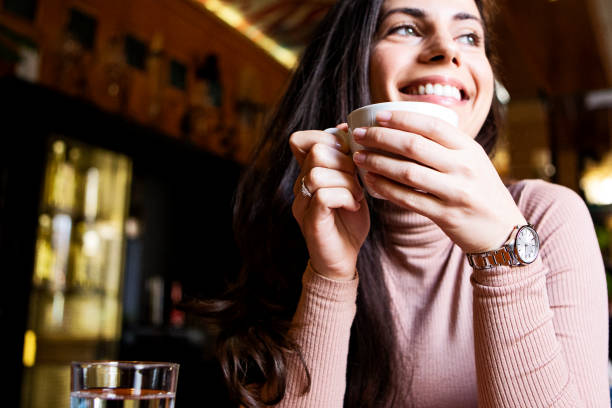 istock Smiling young woman drinking coffee at the cafe 1368972835