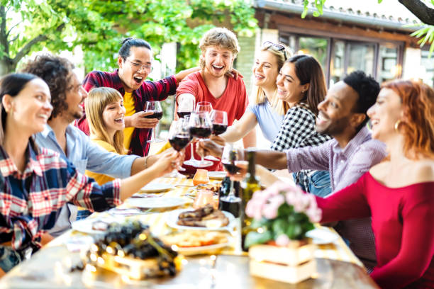happy friends having fun toasting wine out side - young people sharing harvest together at farm house vineyard countryside - youth life style concept - shallow depth of field with focus on central guy - picnic family barbecue social gathering imagens e fotografias de stock