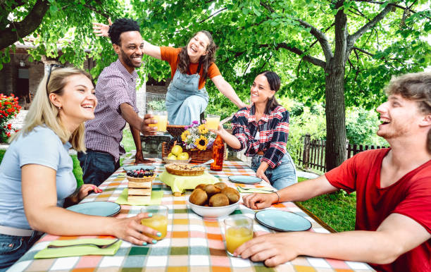 junge männer und frauen stoßen auf gesunden orangenfruchtsaft auf der terrasse des bauernhauses an - lebensstilkonzept mit glücklichen freunden, die am nachmittag gemeinsam spaß haben - heller lebendiger filter - breakfast eating people teens stock-fotos und bilder