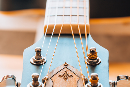 Tensioning the strings on the neck - metal tuning pegs - tuning the guitar