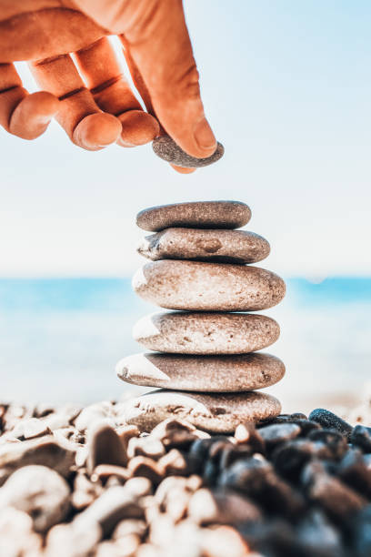 istock A man hand places a smooth stone on a pile of pebbles on the shore 1368974202