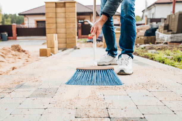 un homme avec une brosse balaie les dalles de pavage sur le chemin près de la maison - sweeping photos et images de collection