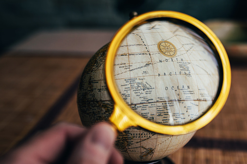 Globe map search for travel directions - view through magnifying glass - vintage terrain plan