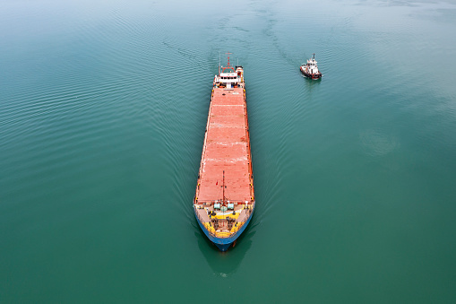 Harbour tugboat guides a cargo ship into the harbour of Samsun - Turkey - Taken with DJI Mavic 2 Pro, You can see more shipping concept images in my portfolio. Aerial drone view of a container ship nearing port with the assistance of a tugboat