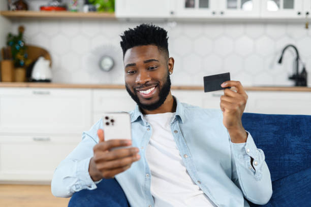 istock Online transaction, payment. Multiracial man holding credit card and using smartphone for shopping, a dark skinned guy with mobile phone and making purchases 1368977281
