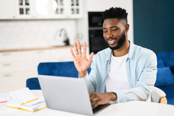 istock Young good-looking man wearing domestic clothes using laptop for video connection with colleagues. Remote meeting, say hi, looking at the webcam, glad to see 1368977711