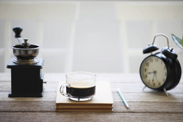 Coffee glass cup and old book and clock on wooden table