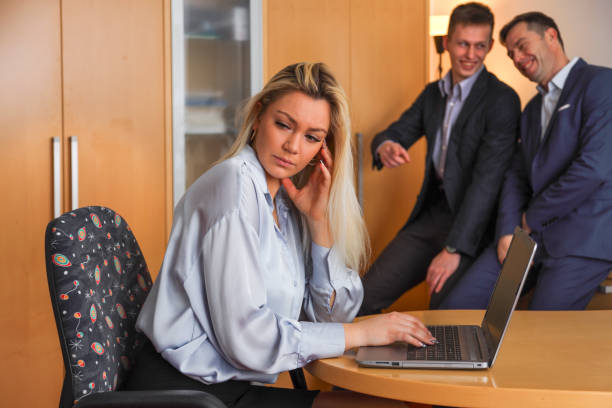 Two businessmen ridicule a working woman stock photo