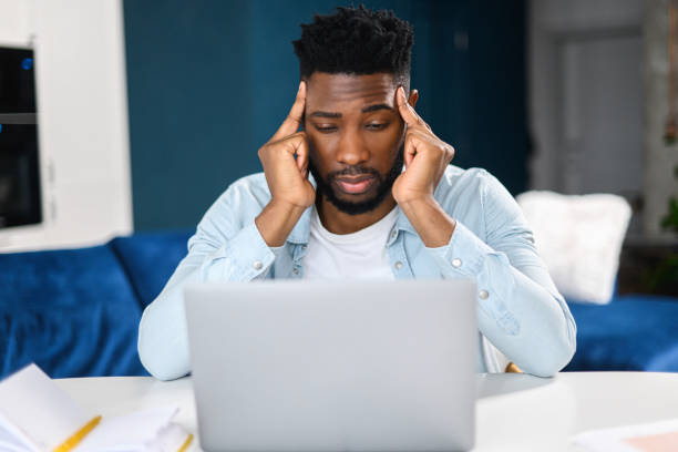 istock Tired male office employee holding hands at his head while looking at the laptop screen, feeling boring and angry. Bored multiracial man in smart casual shirt sitting 1368977896