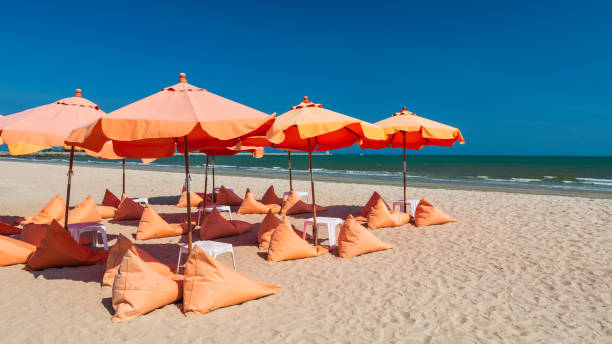 istock Orange umbrellas and bean bag chairs on sand beach 1368978544