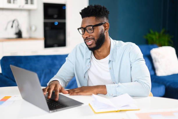 istock Confident concentrated multiracial freelancer guy working on laptop at home office, while sitting at desk and using computer. Brunette man typing on keyboard, enjoying remote work 1368978661
