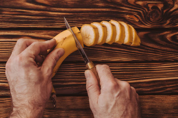 Man cuts banana into rings on board