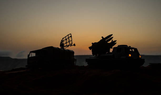 Creative artwork decoration. Silhouette of mobile air defence truck with radar antenna during sunset. Satellite dishes or radio antennas against evening sky. stock photo