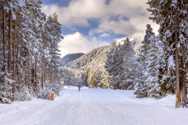 Bansko, Bulgaria, bulgarian winter ski resort panorama with groomed ski road slope and Pirin mountain peaks view