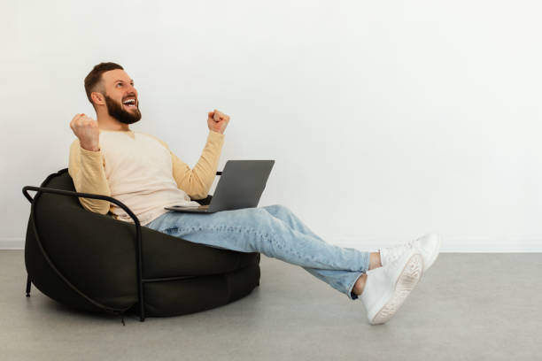 istock Emotional Male Freelancer Using Laptop Gesturing Yes Sitting Indoor 1368981742