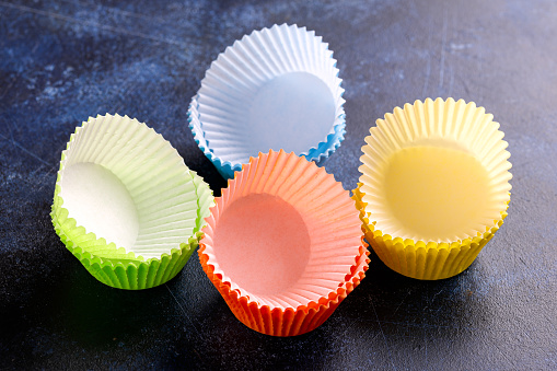 Empty cupcake cases, forms on blue background, table.