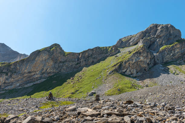 mountain slopes partly covered with grass that reach into the blue summery sky. near the famous mountain pass road Klausenpass in the canton of Uri.