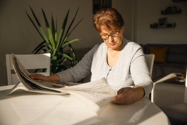 istock Senior woman reading newspaper at home 1368985534