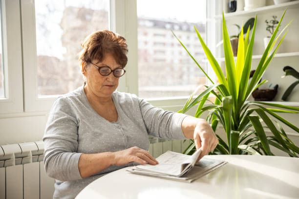 istock Senior woman reading newspaper at home 1368987795