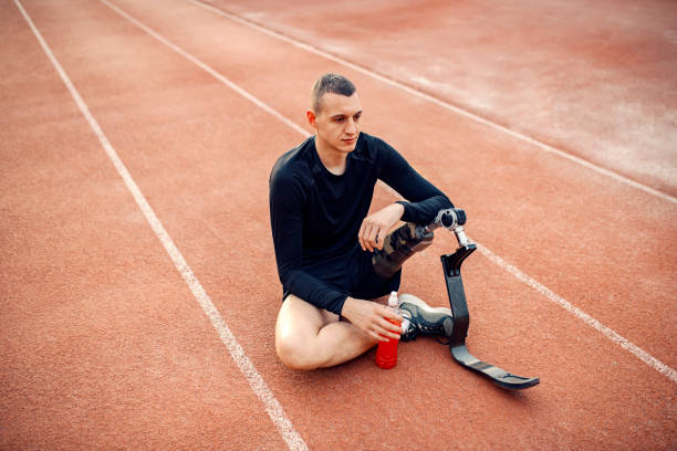 istock A tired runner with prosthetic leg sitting on running track with refreshment in his hand and taking a break. 1368988154