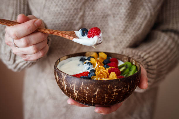 Woman eating healthy breakfast from coconut bowl stock photo