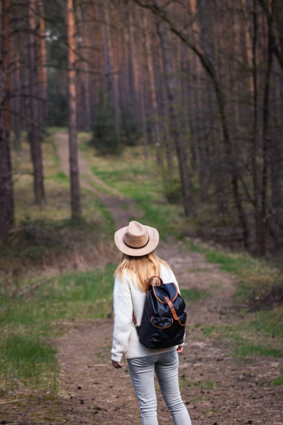 istock Woman with cowboy hat and backpack hiking on footpath in forest 1368992288