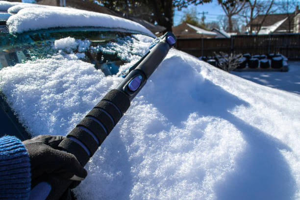 車のフロントガラスから雪を削る - 手袋と影とアイススクレーパーを伸縮する手 - 選択的な焦点。 - snow car window ice scraper ストックフォトと画像