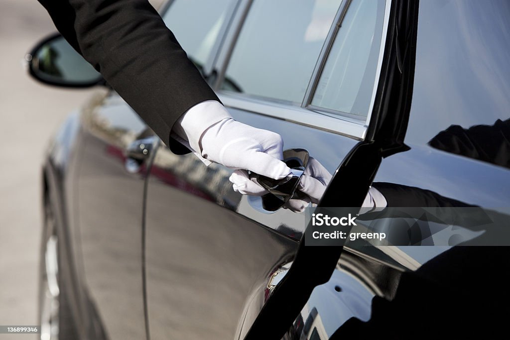 Chauffeur opening / closing luxury car door The white gloved hand of a uniformed chauffeur / doorman opening / closing a luxury car door. Chauffeur Stock Photo