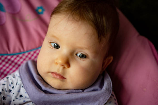 Baby  is looking to the person in front of her.