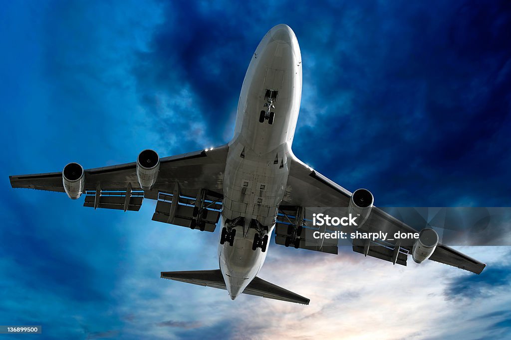 jumbo jet airplane landing at dusk Above Stock Photo