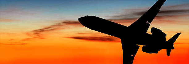 corporate jet airplane in close-up silhouette flying at dusk, panoramic frame