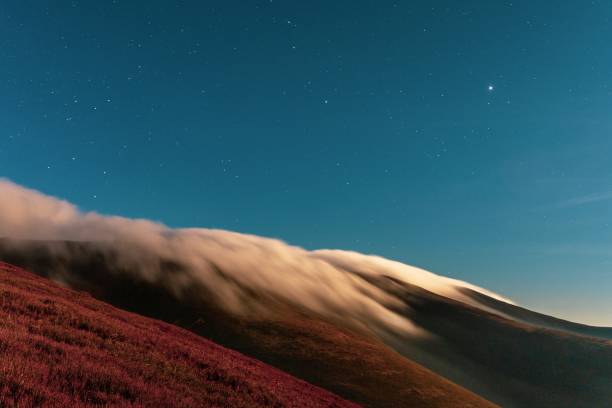 Thick fog covering mountain hills at bright night