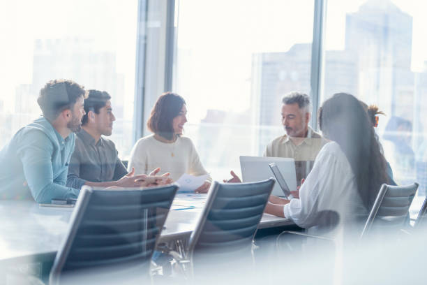 Diverse group of Business people during a meeting with copy space. Diverse group of Business people during a meeting with copy space. They are sitting in a board room, All are casually dressed. business meeting stock pictures, royalty-free photos & images