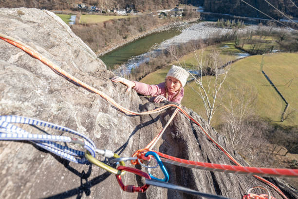 Female rock climber moves up steep wall