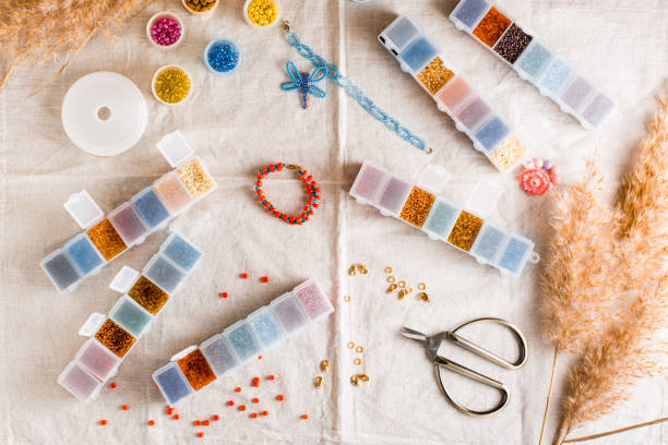 istock Items for beading - boxes with beads, thread and scissors on the table. Creative leisure, home teaching crafts for children. Top view. 1369002724
