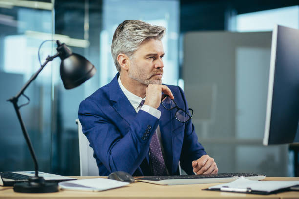istock Portrait of a man, businessman thinking while working in the office at the computer 1369002893