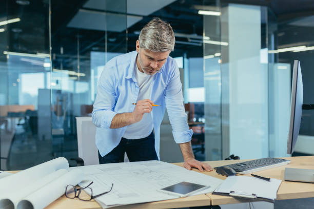 istock An experienced architect working on a drawing, a man in a modern office at the computer, a designer draws a modern project 1369002915