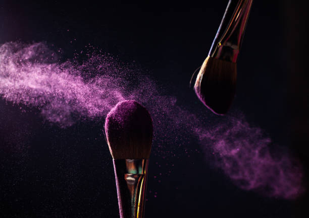 istock Make-up brushes with pink or violet powder explosion on dark background 1369004719