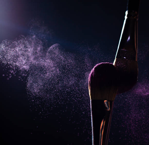 istock Make-up brushes with pink or violet powder explosion on dark background 1369005171