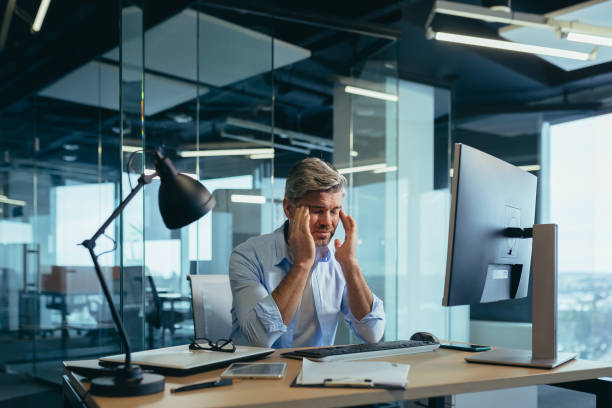 istock An experienced gray-haired businessman works at the computer until late, tired has a severe headache, stress and depression 1369005555
