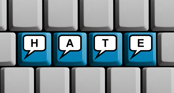 Blue computer keyboard showing hate in speech bubbles