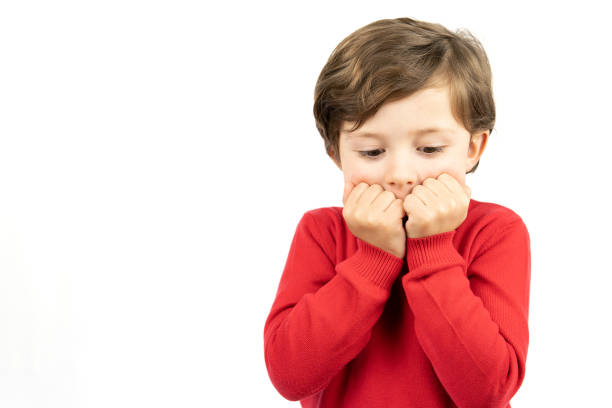 Cute scared little child boy in sweater looking at the camera on white background. Human emotions and facial expression
