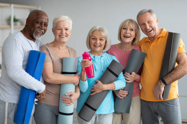 gruppo di pensionati atletici che frequentano lezioni di yoga presso il centro di ritiro - yoga exercising outdoors group of people foto e immagini stock