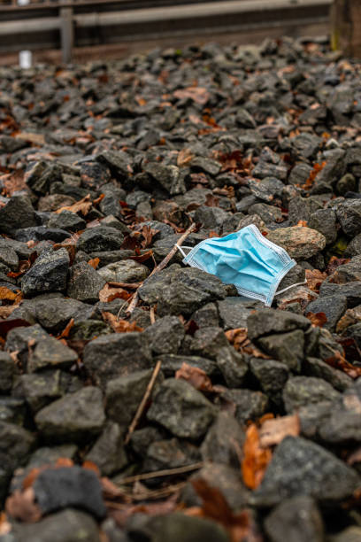 istock A lonely blue face mask thrown away on some stones.. 1369010498