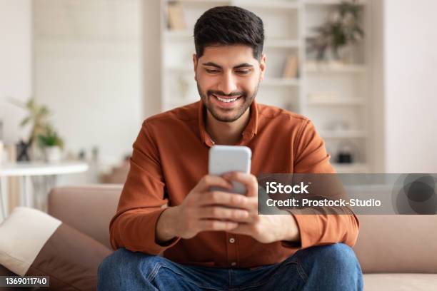 Portrait Of Smiling Arab Man Using Smartphone At Home Stock Photo - Download Image Now