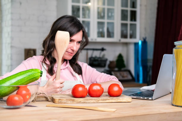 istock Woman cooking diet food pasta according the tutorial of a online virtual master class.  pasta with zucchini and tomatoes. 1369011833
