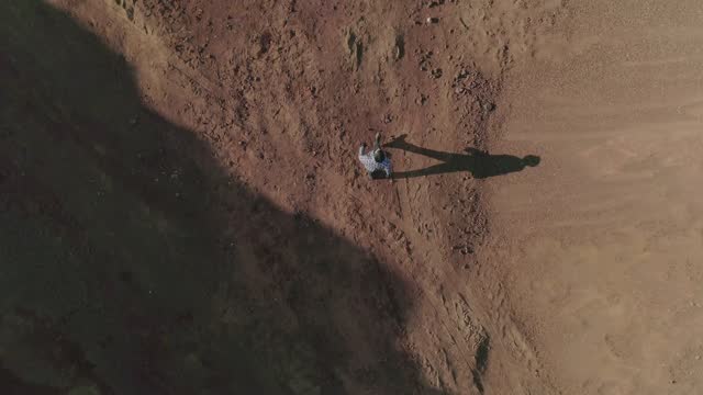 Top view from above . Young man dressed in original costume standing and walking in abandoned land like desert or another planet .  Boy get lost in wasteland . Slow motion . Shot for video clip .