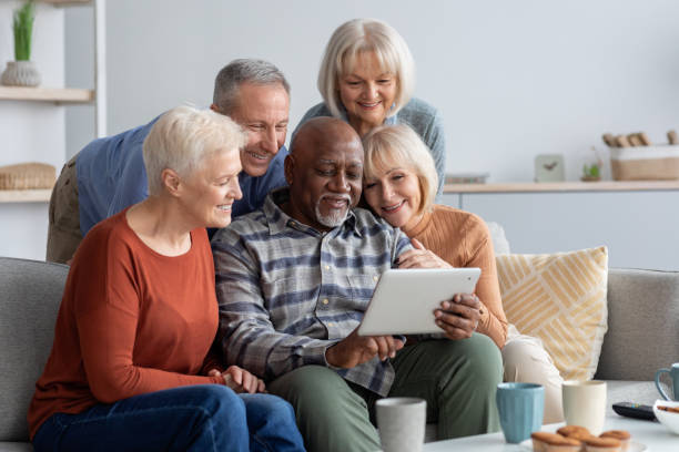 istock Happy elderly people spending time together at home, using gadgets 1369012104